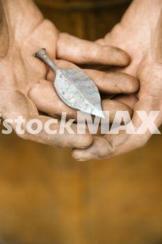 Metallic Ready file. Dirty caucasian male metalmith´s hands holding metal leaf.