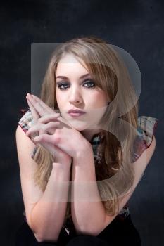 Beautiful dirty-blond girl sitting with hands together next to her face