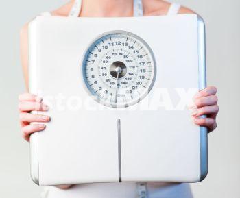 Metallic ready file. Close-up of a young woman holding a scales with focus on scales