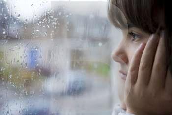 young child looking out of window on rainy day