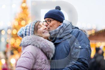 love, winter holidays and people concept - happy senior couple kissing at christmas market. happy senior couple kissing at christmas market