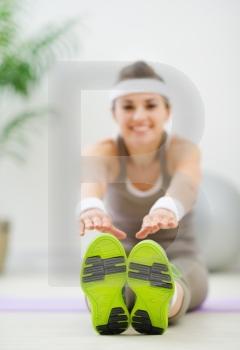 Slim woman doing leg stretching exercises. Focus on sneakers
