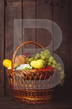 Basket of vegetables and fruits over wooden background