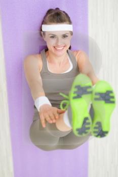Smiling fitness woman on fitness mat stretching