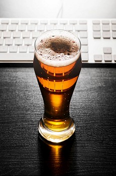 glass of fresh lager beer with keyboard on black table