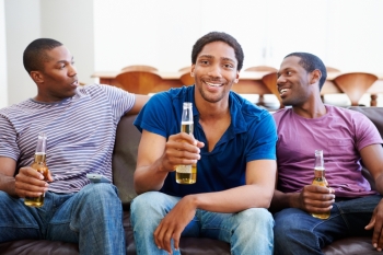 Group Of Men Sitting On Sofa Watching TV Together