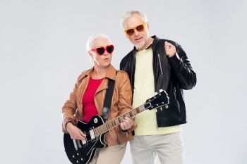 music, age and people concept - happy senior couple in sunglasses with electric guitar. senior couple in sunglasses with electric guitar