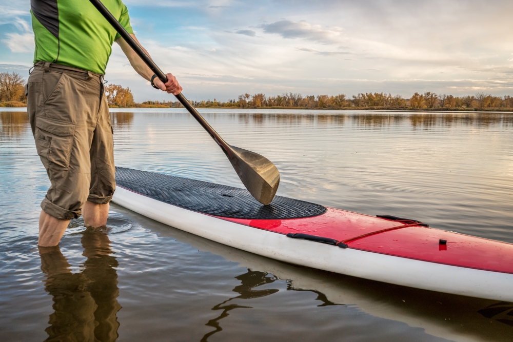 male paddler is starting  paddling workout on his stand up paddleboard on a lake in Colorado