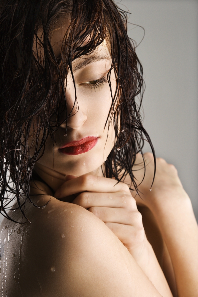 Portrait of bare attractive Caucasian redhead young woman with wet hair and skin.