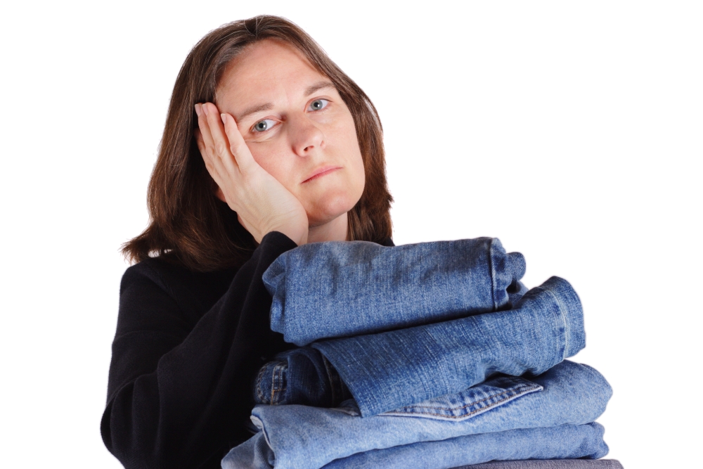 A woman rests her head on her hand while holding a pile of folded clothes