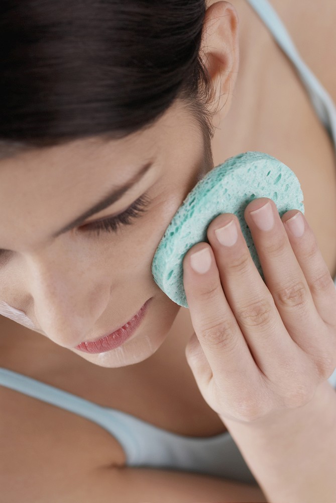High angle view of a young woman scrubbing her face with a sponge