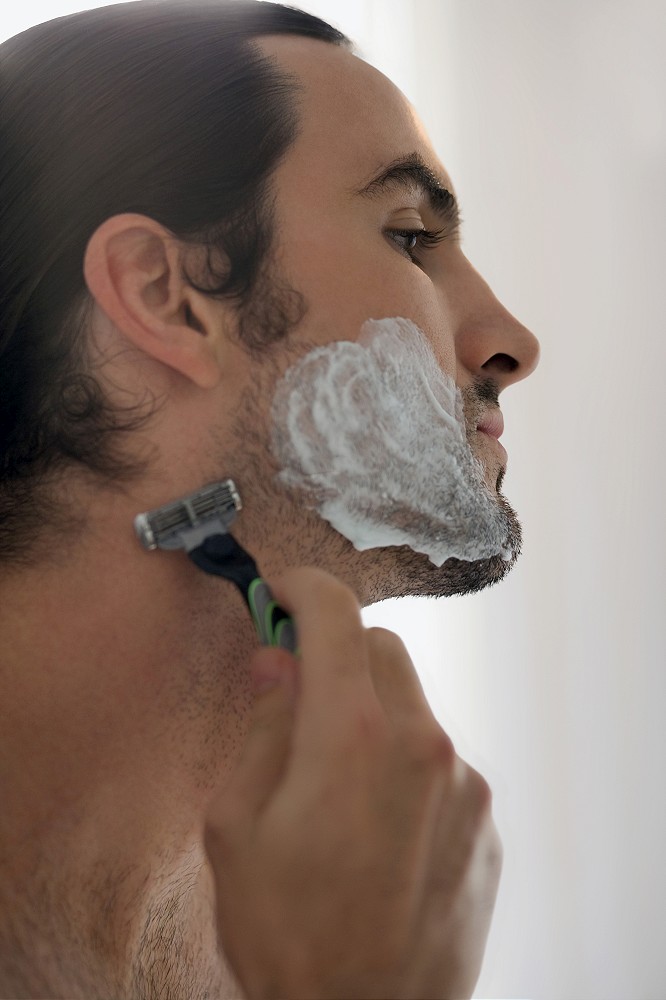 Close-up of a young man shaving with a razor