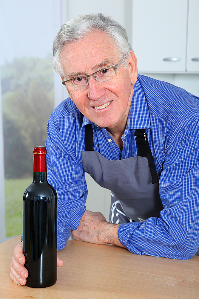 Elderly man holding bottle of red wine