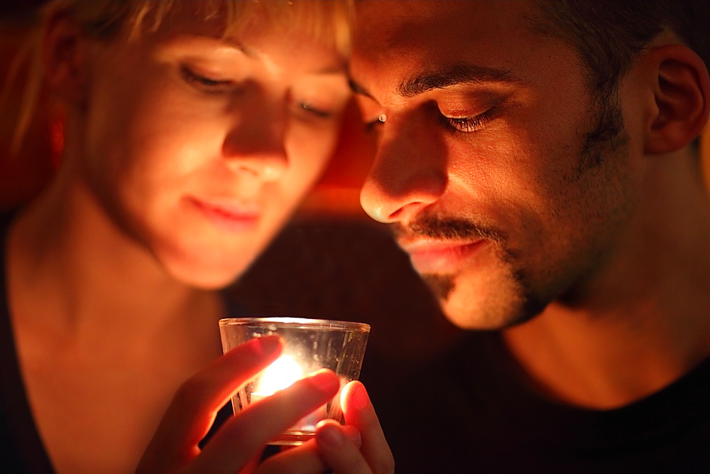 man and woman keeping glass candle and looking at it. focus on man&acute;s left eye.