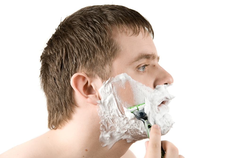 Man shaving razor with foam on white