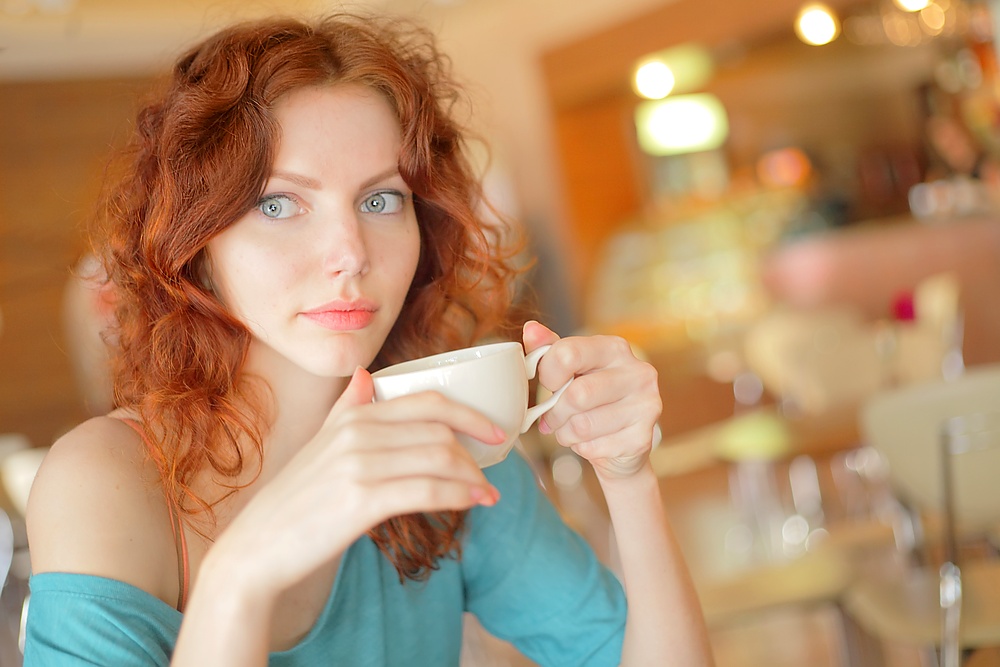 Beautiful young woman with a cup of coffee at a cafe