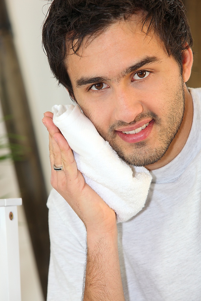 Young man pressing a towel to his face