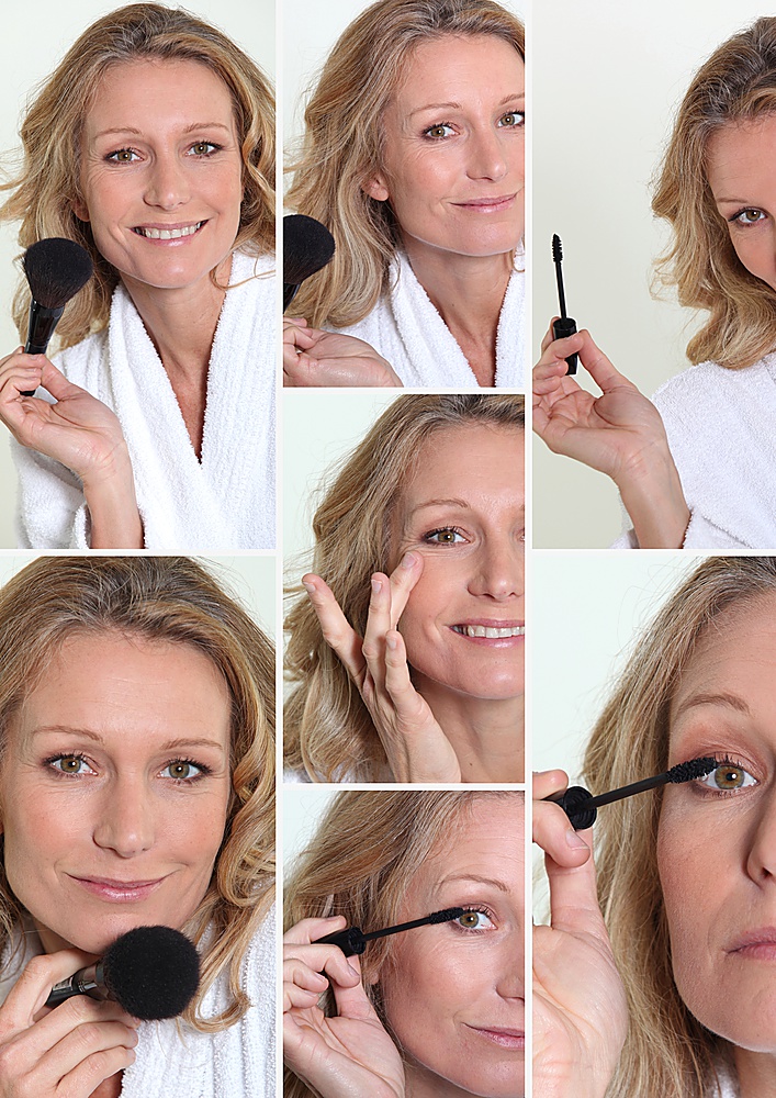 Woman in bathrobe putting make-up on