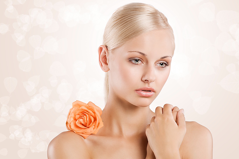 sweet portrait of young cute girl with an orange rose on her naked shoulder