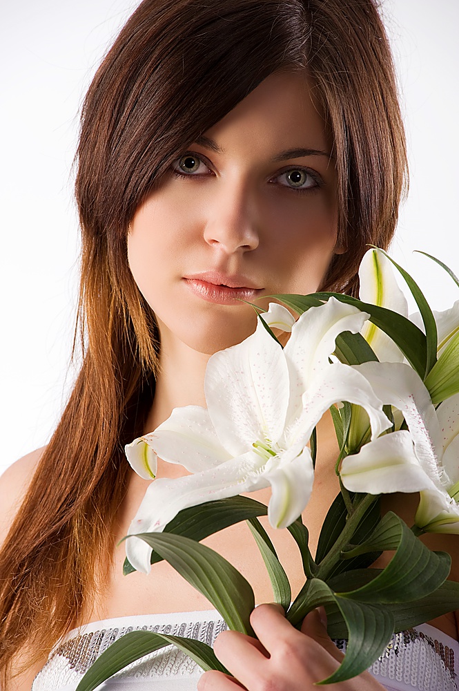 pretty and young sweet girl with dark hair and some white lily looking in camera