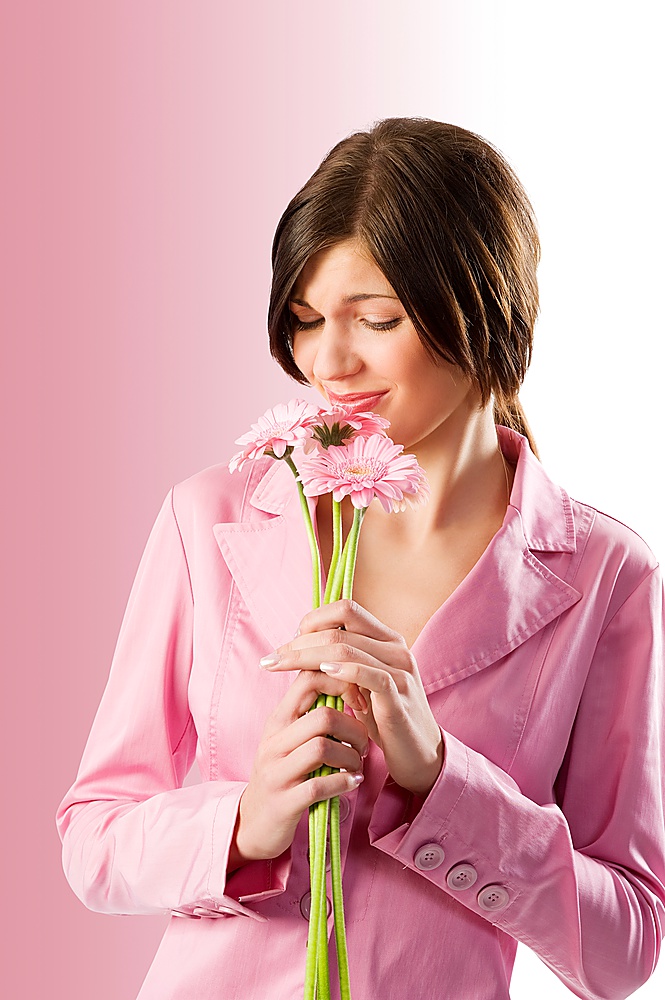 cute young brunette smelling pink flowers and making funny face