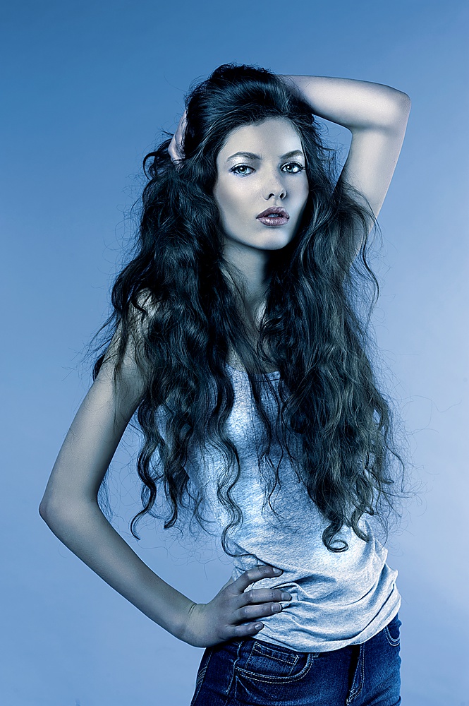 blue fashion  portrait of a young girl with curly long hair looking in camera