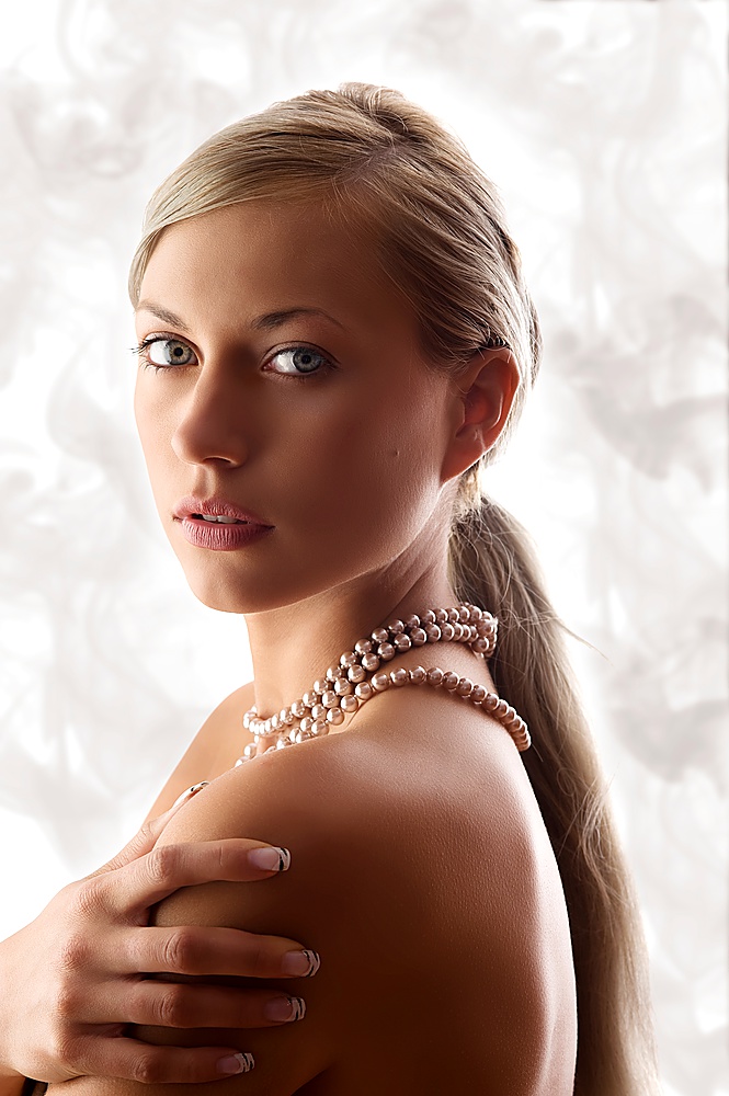 blond and pretty woman with pearl necklace looking in camera