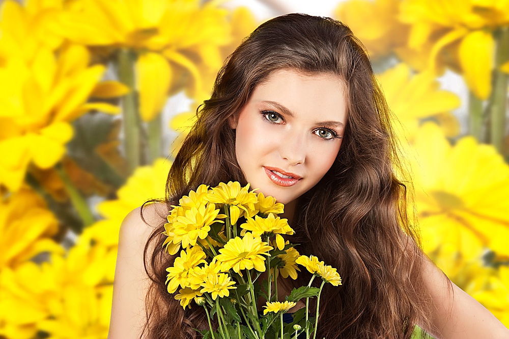 Beautiful fashion portrait of a young and fresh woman taking a bouquet of yellow flower