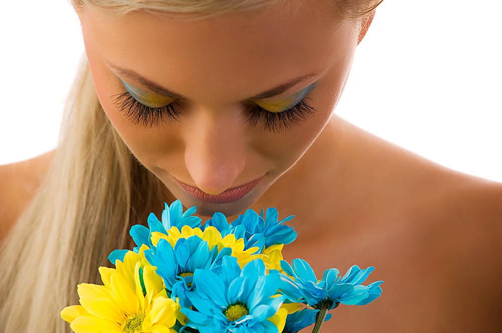 cute blond woman with colored make up in act to smell some daisy