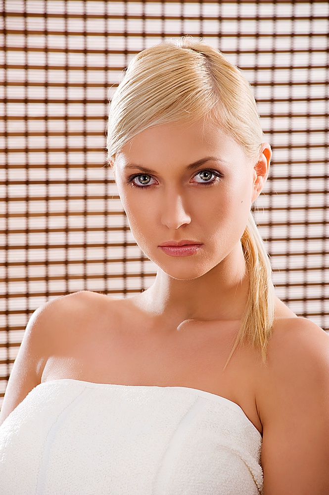 beauty advertising portrait of blond girl with white towel and a wood curtain behind