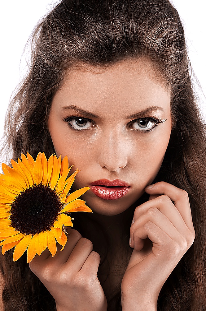 beauty shot of a beautiful young girl with long curly hair holding a sunflower in her hand