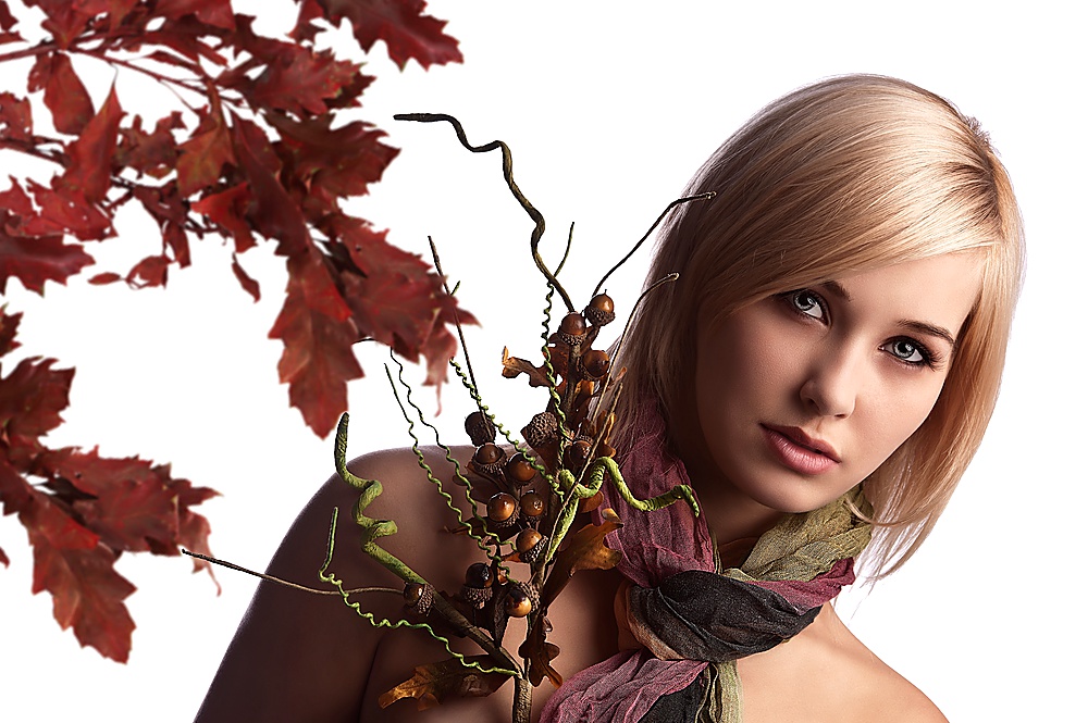 beauty portrait of a blond and pretty girl with scarf looking into the camera and holding an autumn bouquet of flowers