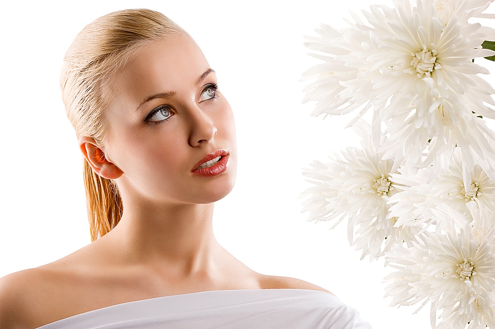 beauty portrait of young cute blond girl with white top looking at some flowers