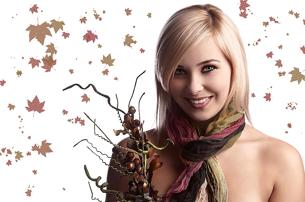 blond and pretty girl with atumn scarf looking in camera and holding an autumn bouquet of flowers