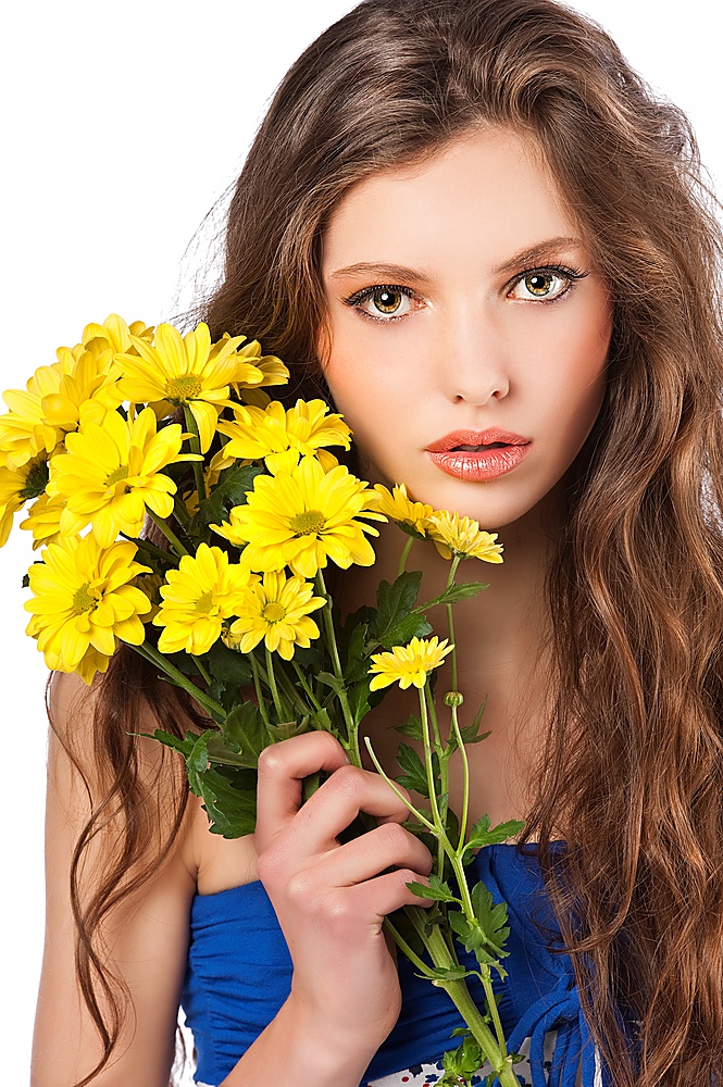 Beautiful fashion portrait of a young and fresh woman taking a bouquet of yellow flower and looking in camera