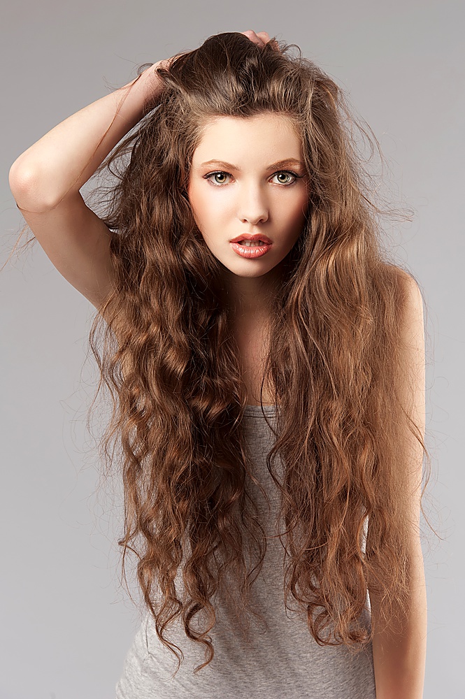 long curly hair young cute girl in a porteait on gray background