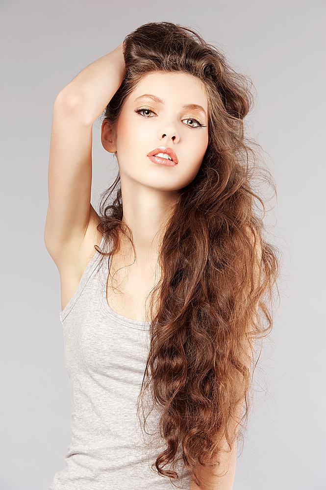 pretty girl with very long curly hair in a fashion portrait looking in camera