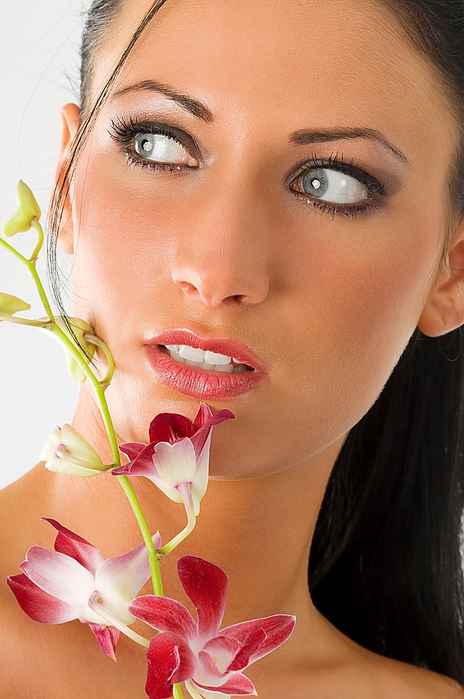 beauty portrait of cute woman with blue eyes and pink orchid