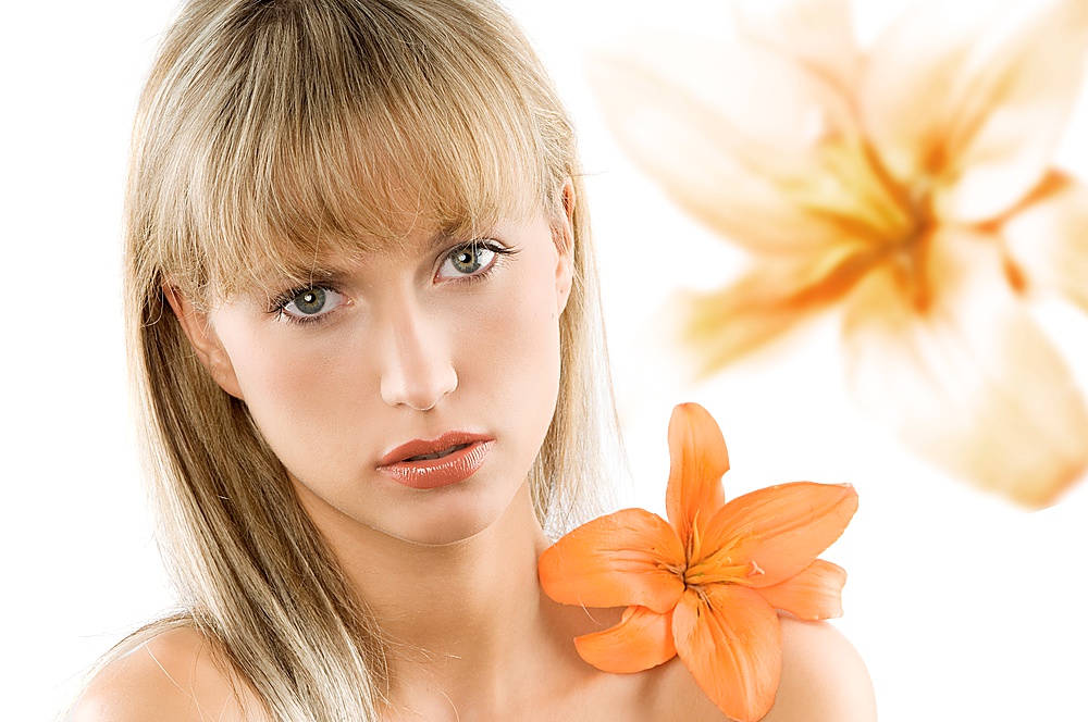 blond and young beautiful woman with an orange flower on her shoulder