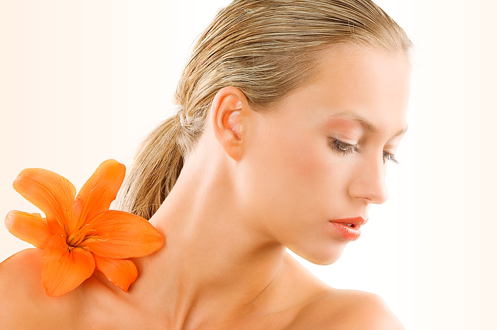great portrait of a blond girl with an orange flower on her shoulder