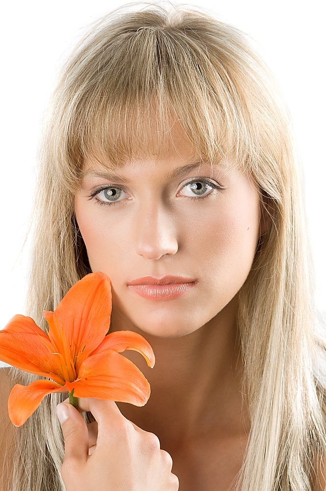 fresh and beautiful portrait of a woman with blond hair keeping an orange lily