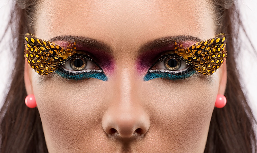 beauty close-up portrait with colored and feathered make up, looks in to the lens