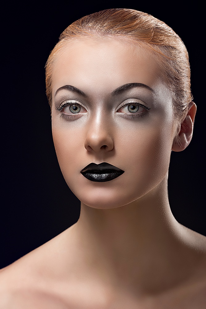 beauty close-up portrait of young woman with sensual look, dark lipstick, bright eye make-up, blonde hair and black background
