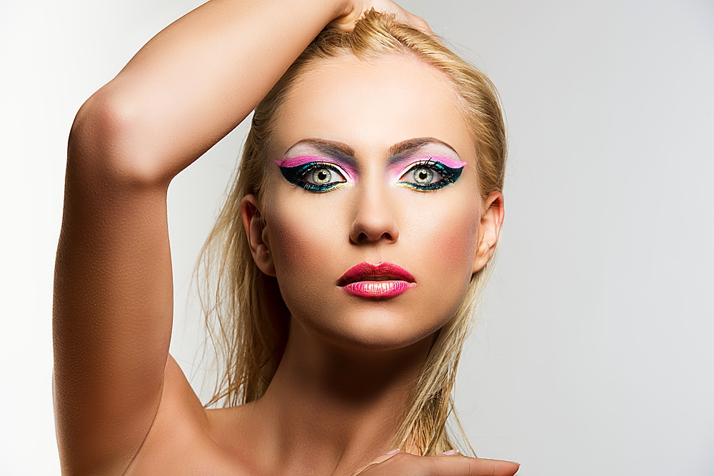 beautiful blonde girl with showy make up, her right hand is on the head and she looks in to the lens