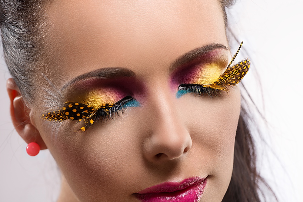 beauty close-up portrait with colored and feathered make up, her eyes are closed