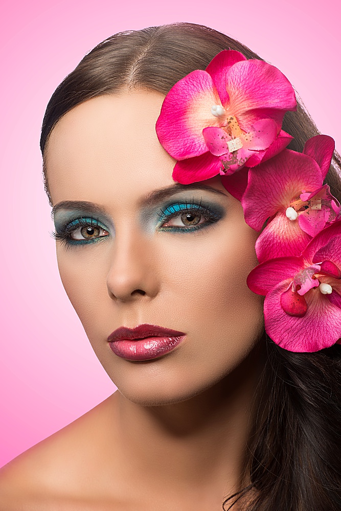 close up beauty portrait of young cute brunette with pink flower. FLOWERS ARE FAKE