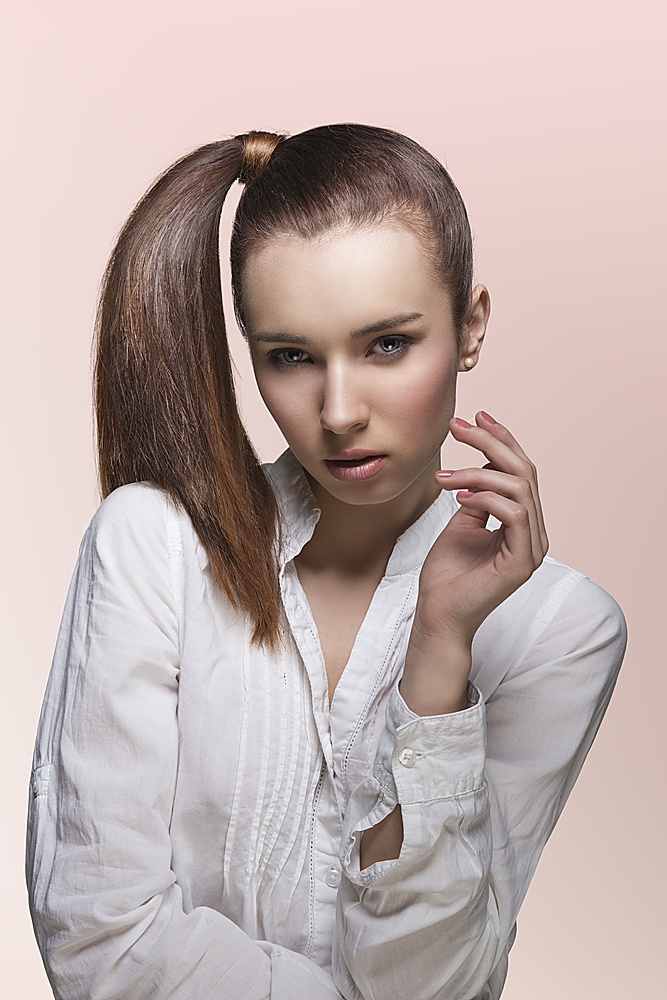 sensual young lady with brown hair, white shirt and brown smooth ponytail looking in camera