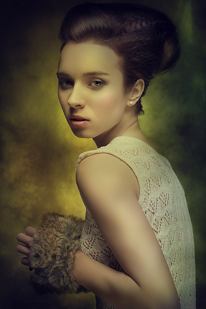beautiful young girl with brown fashion hairdo looking in camera and taking in the hand fur accessory