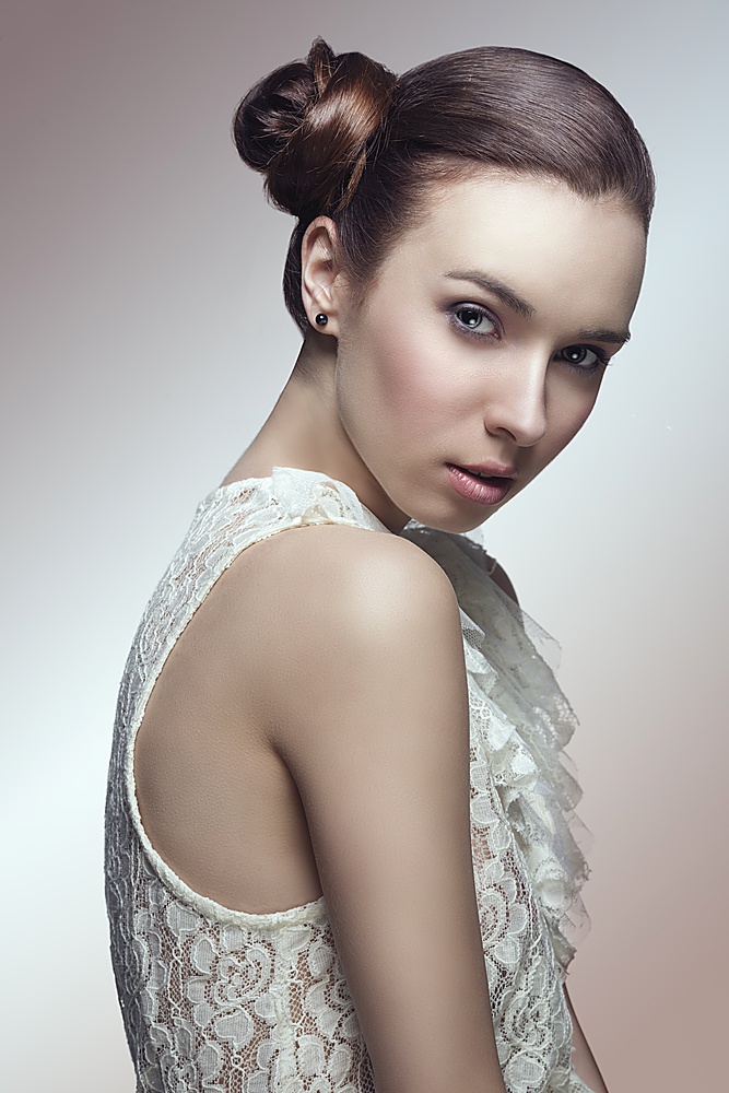 sensual young girl with brown hair tied in lateral chignon hair-style looking in camera and wearing sexy lace shirt
