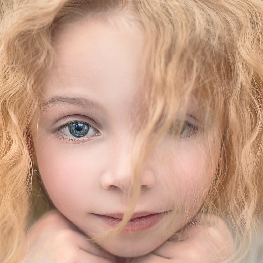 portrait of a beautiful young lady with curly blonde hair and a gentle manner
